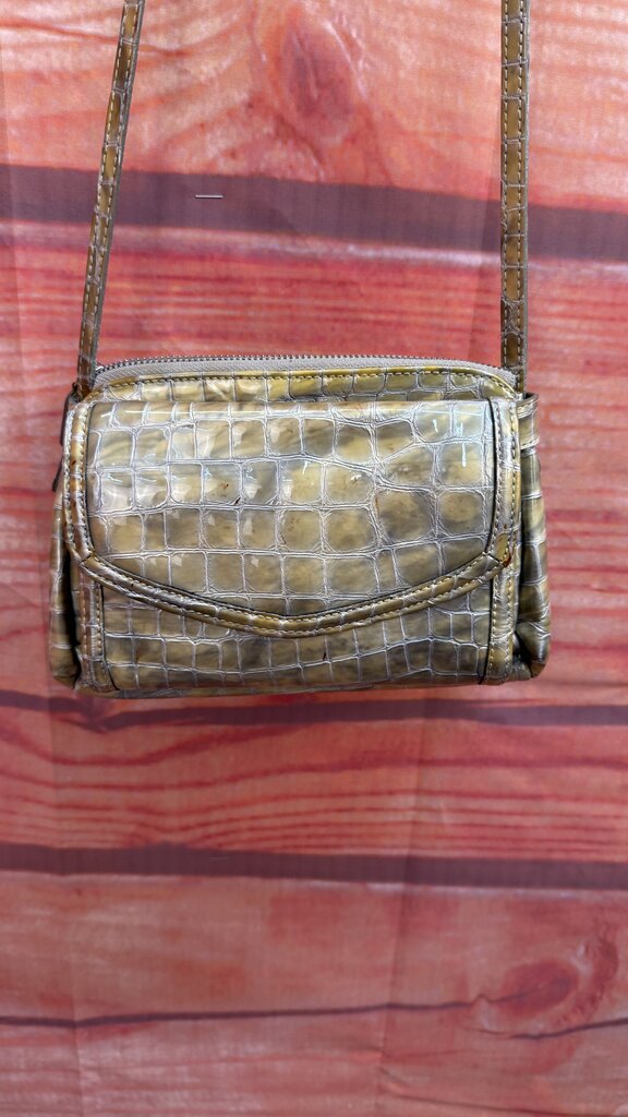 Green crocodile-patterned handbag on a red and brown striped fabric background