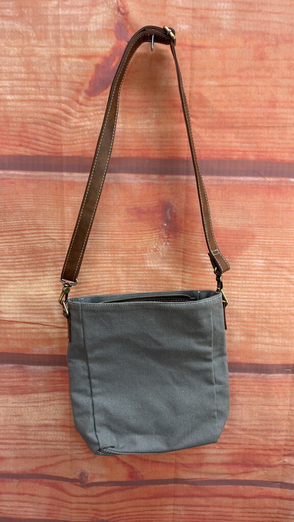 Gray shoulder bag with brown strap on a wooden surface