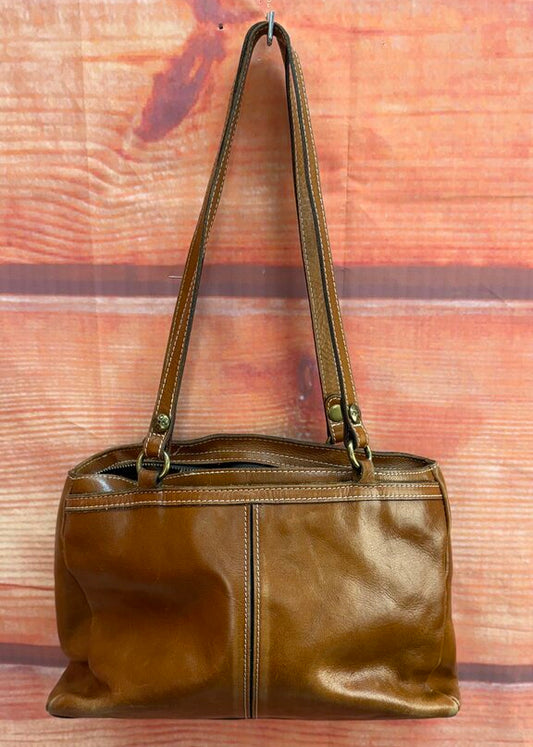 Brown leather handbag on a wooden surface