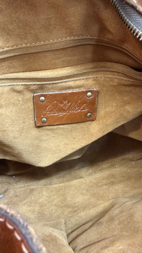 Close-up of a brown leather bag with a brand label.