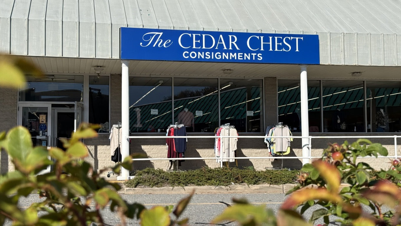 Building exterior with 'The Cedar Chest Consignments' sign, surrounded by greenery.